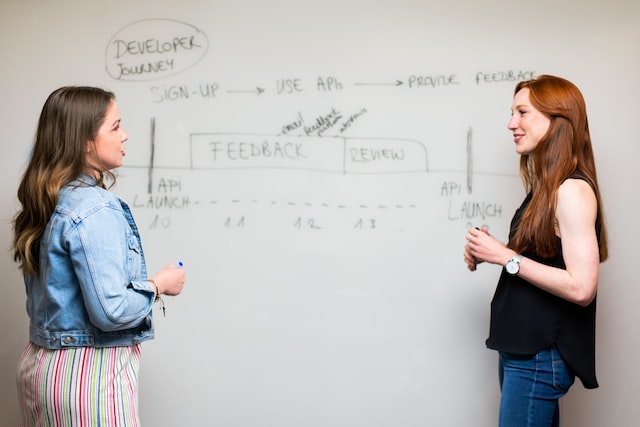 Teaching assistant and teacher discussing standing near a whiteboard